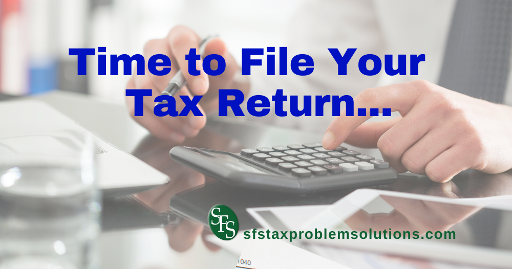 Time to file your tax return -man's hands with calculator